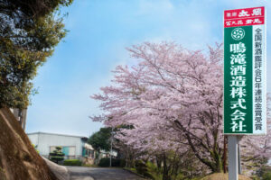 la rue menant à la maison narutaki avec la pancarte écrivant "Narutaki Shuzou Kabushikigaisha"