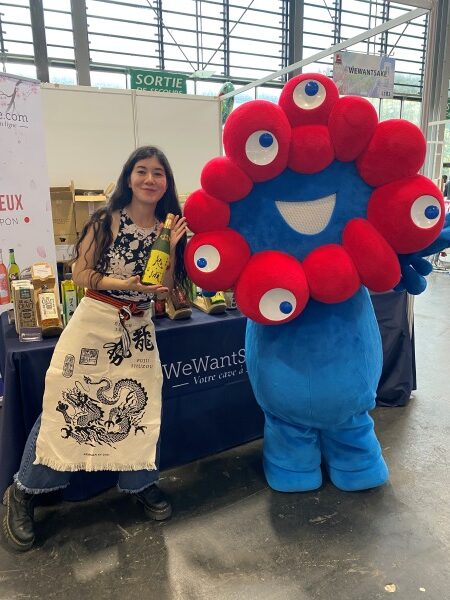 Stand WeWantSake à la Japan Expo, staff avec MyakuMyaku, mascotte d'Osaka Expo